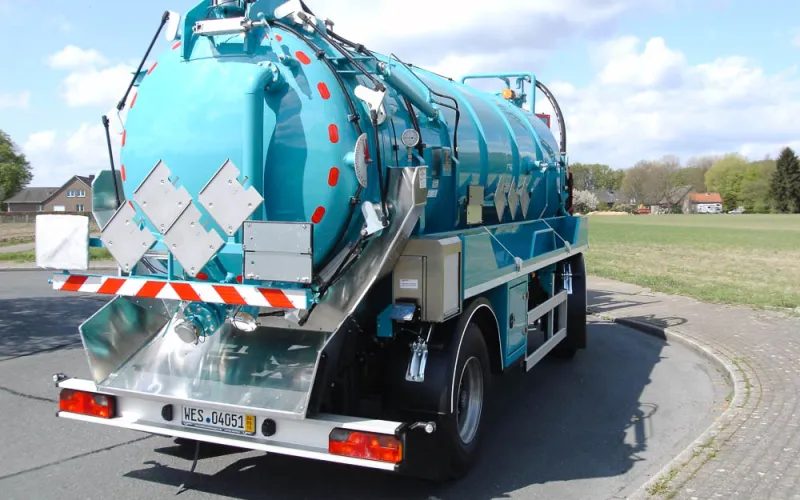 Turquoise two-axle vacuum trailer with stainless steel rear apron, rear view