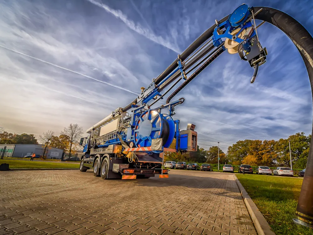 Blue KROLL combination vehicle with large vacuum-pressure tank and suction boom in front of the plant