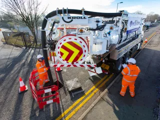 Combination vehicle at work on a sewer manhole, two workers in high-visibility clothing