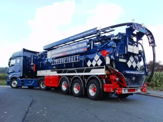 Blue three-axle vacuum semi-trailer with suction boom, rear view