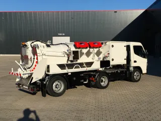 White vacuum truck on a compact two-axle chassis in front of the KROLL hall