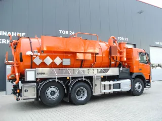Orange three-axle vacuum truck with stainless steel substructure in front of the production hall