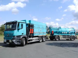 Turquoise multi-compartment vacuum truck coupled to a vacuum trailer