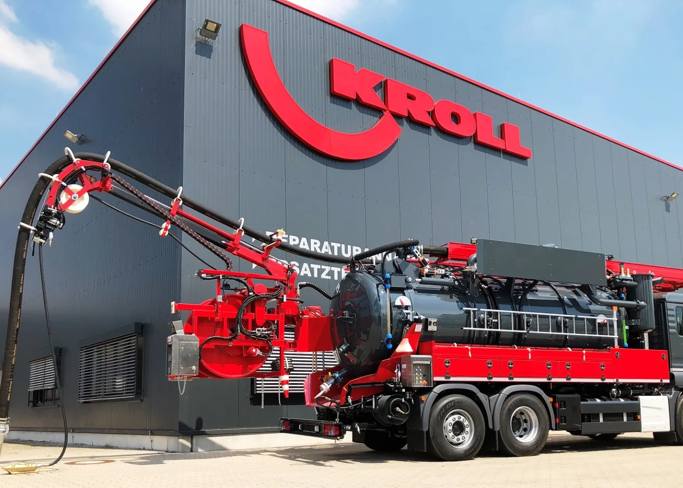 Red and black KROLL combination vehicle with slewing boom in front of the production hall in Hünxe